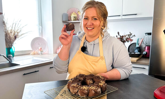 Rezepte & Inspirationen: Monika Nagl zeigt lächelnd ihre Schokoschnecken mit Nuss-Nougat-Creme und Butter von GOLDSTEIG.